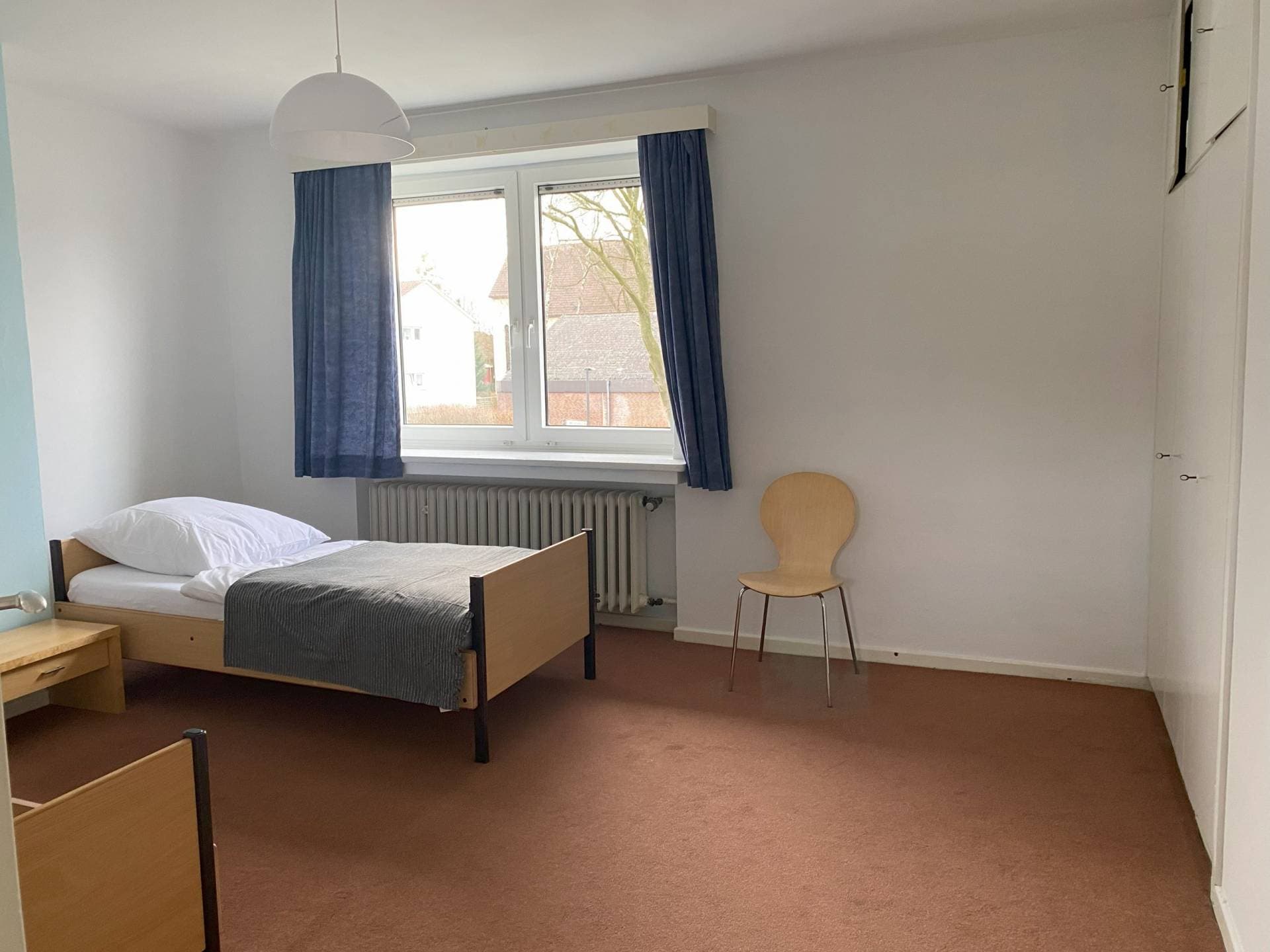 Geräumiges Einzelzimmer mit blauen Vorhängen – Haus An der None